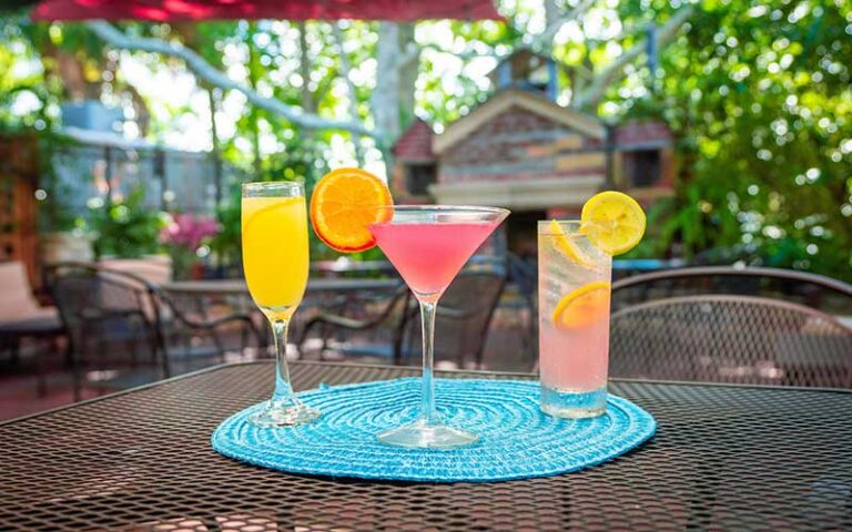 three cocktails on patio table with wooded background at cafe karibo fernandina beach amelia island