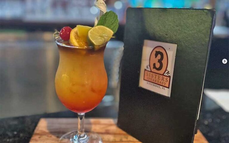 tropical cocktail with brand menu on tabletop at 3 sisters speakeasy kissimmee