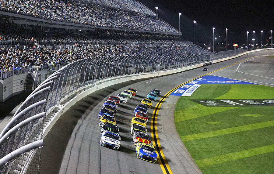 two rows of stock cars racing along curving track at daytona international speedway daytona beach