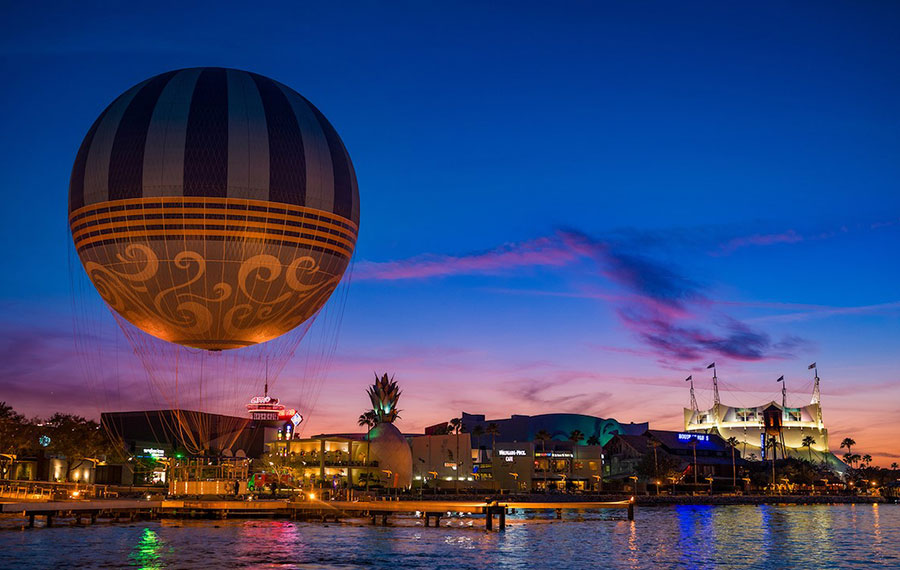 view from water of sunset with skyline of balloon ride and buildings at disney springs