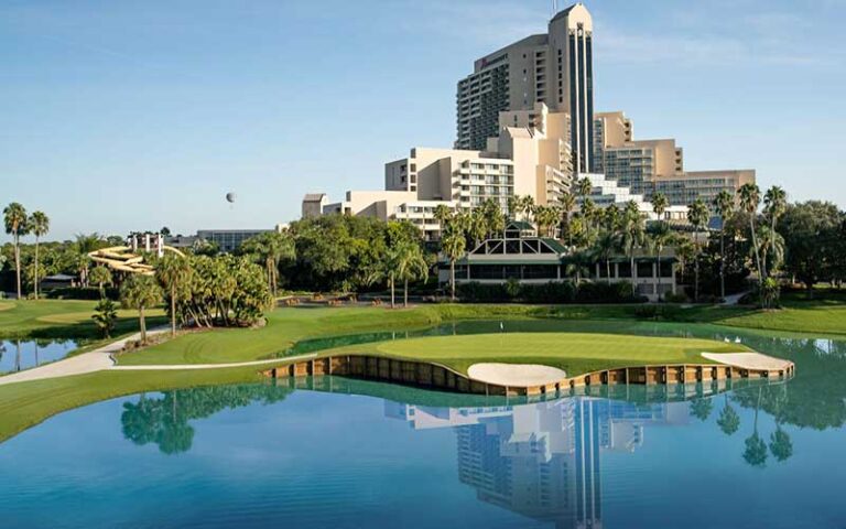 view of high rise hotel with golf course and lake in foreground at orlando world center marriott