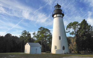 white lighthouse with black top and storage building in clearing at amelia island lighthouse fernandina beach