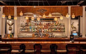 wooden bar with bottles and craft lighting at liberty bar restaurant tallahassee