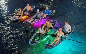 aerial view of four couples clear kayaks on water at glow paddle pensacola beach