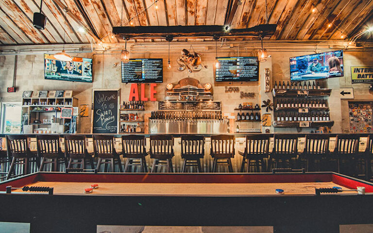 bar area with seating and shuffleboard at swan brewing lakeland