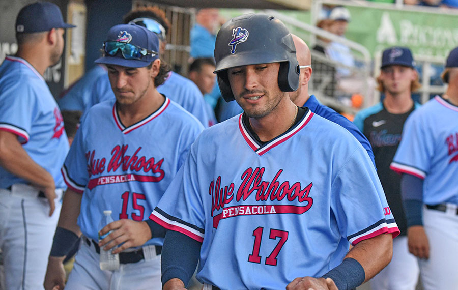 baseball players walking in dugout with pensacola blue wahoos jerseys