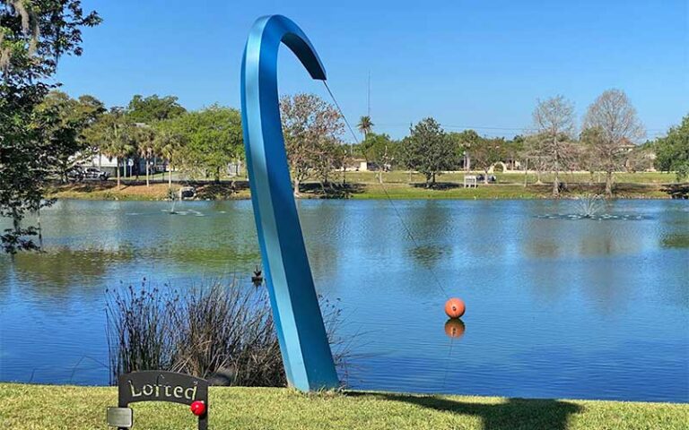 bent fishing rod sculpture along edge of lake at tuscawilla park ocala