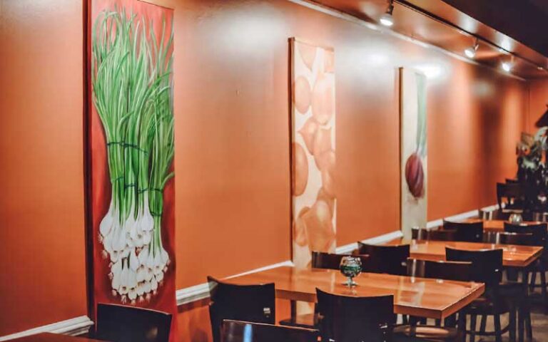 dining area with orange wall and onion paintings at braised onion ocala