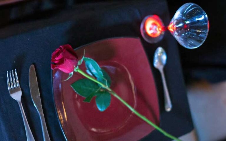 dinner setting with rose on black tabletop at tallahassee date night