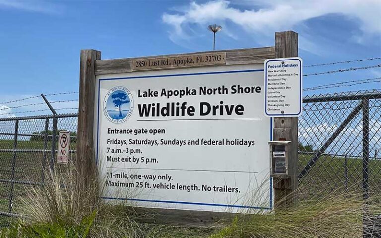 drive entrance sign with posted hours and fence gate at lake apopka wildlife drive