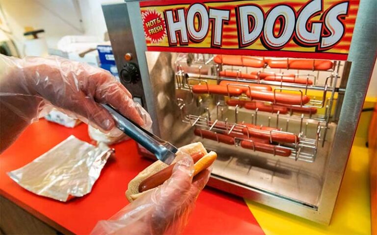 hands serving hot dogs in concession area at ocala drive in