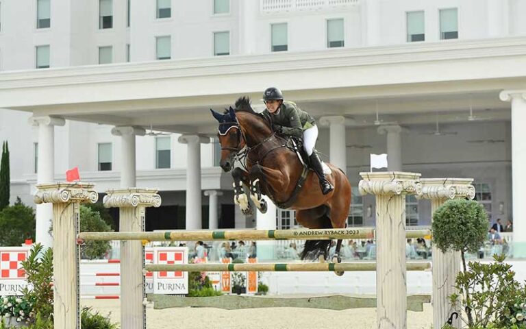 horseback rider jumping plinth with hotel in background at the equestrian hotel ocala