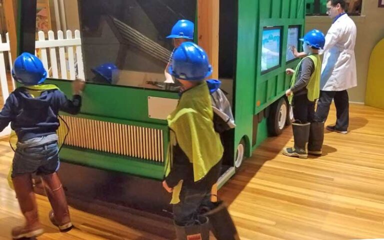 kids wearing gear playing with garbage truck display at discovery center ocala