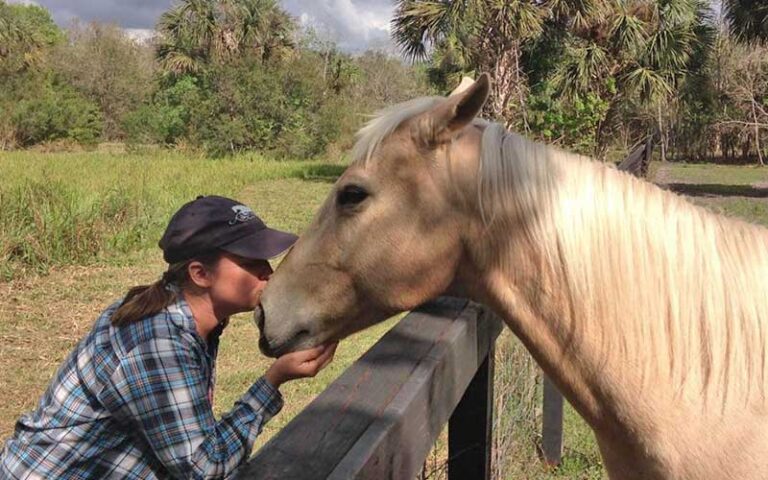 lady kissing light colored horse over fence at hidden palms ranch sanford orlando