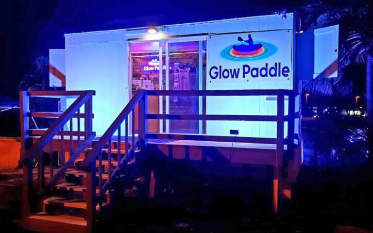 night exterior of dockside building with sign at glow paddle pensacola beach