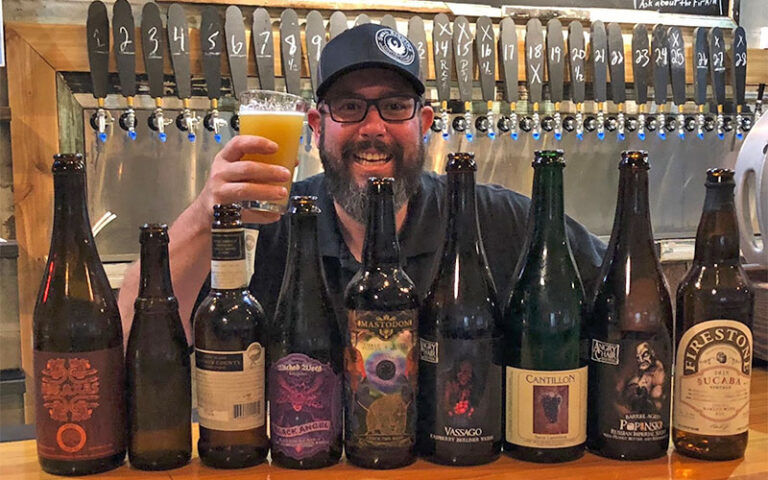 owner with selection of beer bottles and taps at swan brewing lakeland