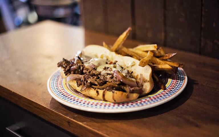 philly cheesesteak with fries entree on bar at brooklyns backyard ocala