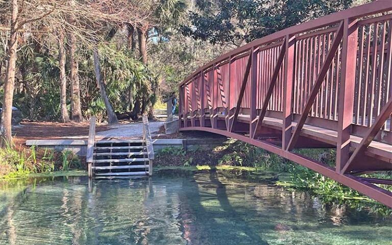 red metal footbridge across clear water with steps at kelly park rock springs apopka orlando