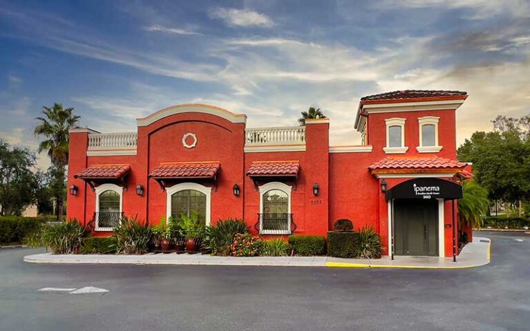 red stucco exterior of restaurant with sign and entrance at ipanema brazilian steak house ocala