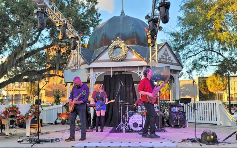 rock band performing on stage with lighting rigs at twilight at ocala downtown square