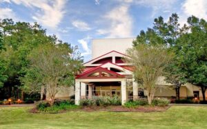 theater building with maroon roofs in trees with lawn at ocala civic theatre