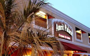 twilight exterior view of sign above entrance with palm leaves at amrit palace ocala