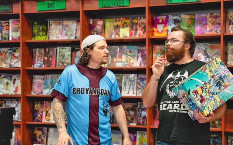 two employees with branded shirts handling merchandise at bearded browncoat comics games ocala