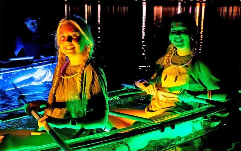 two young ladies in colorfully lit kayak at night at glow paddle pensacola beach