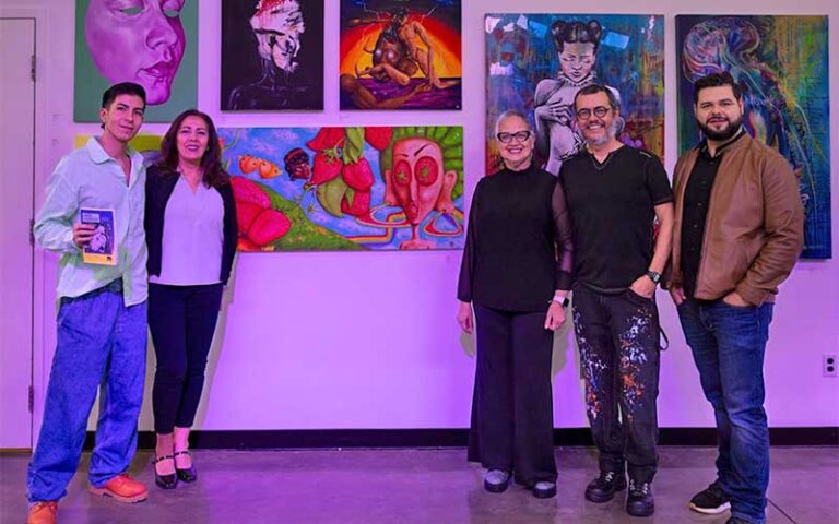 artists standing with paintings on wall at arts garage delray beach