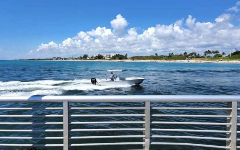 boat speeding past toward beach with rails at ocean inlet park boynton delray beach