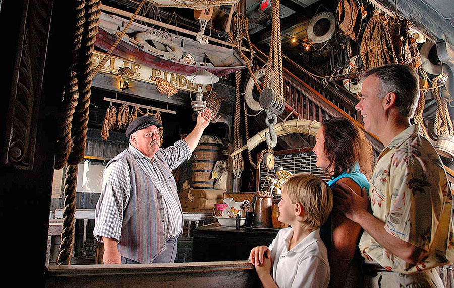 costumed guide talks to father and son in museum exhibit area key west shipwreck museum