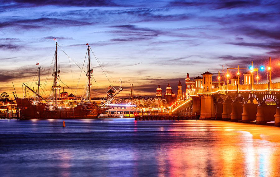 galleon ship with lighted bridge on water with colorful sunset sky clouds and reflection st augustine