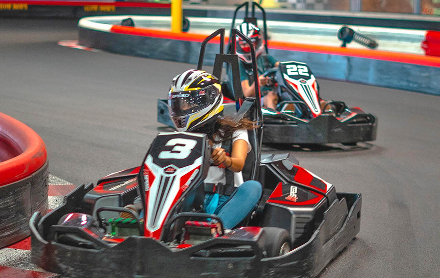 man and woman racing go karts on track k1 speed indoor karting