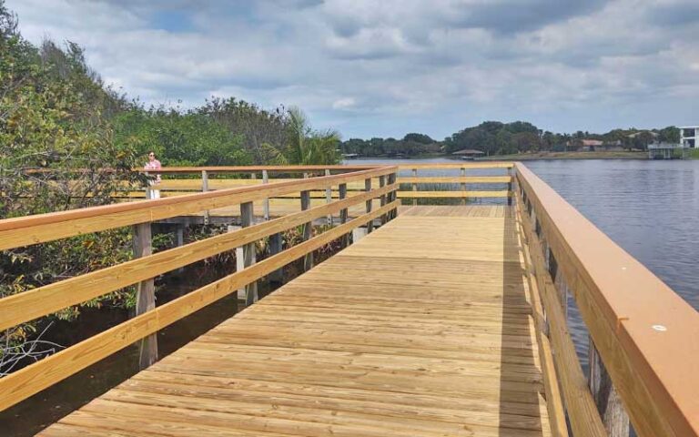 new wooden boardwalk over lake with shrubs and woman at lake ida west park delray beach