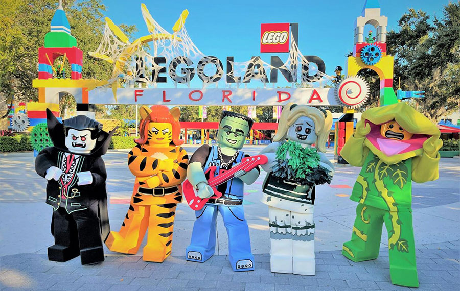 row of monster lego costumed characters with front gate at legoland florida resort