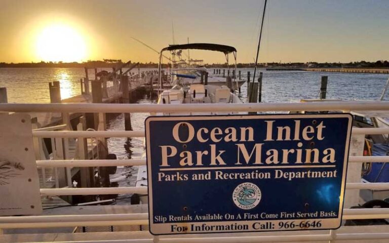 sign on marina rails with boat and sunset over water at ocean inlet park boynton delray beach