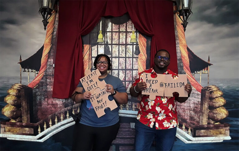 smiling couple posing with signs at end of escape game at xscape our rooms st augustine