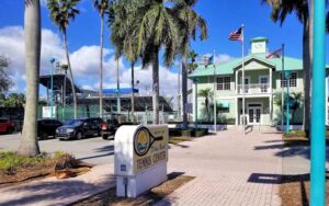 two story building with metal roof courtyard and sign at delray beach tennis center