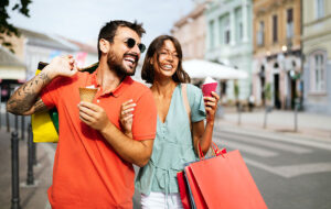 young happy couple with shopping bags on sunny city street