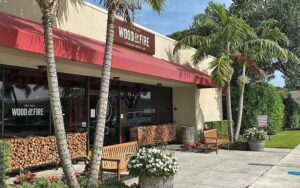 sidewalk view of exterior with entrance and palms at wood fire delray beach