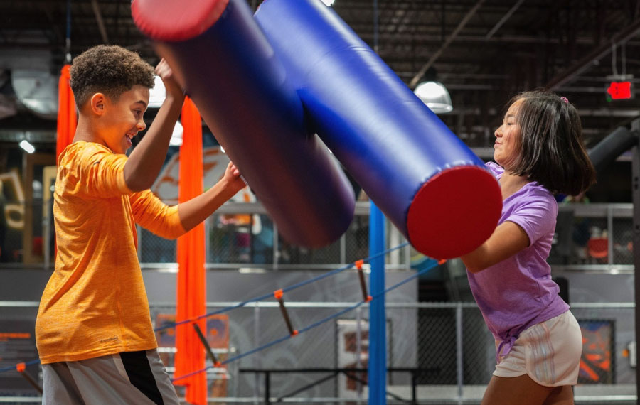 boy and girl jousting with foam sticks at sky zone trampoline park pensacola