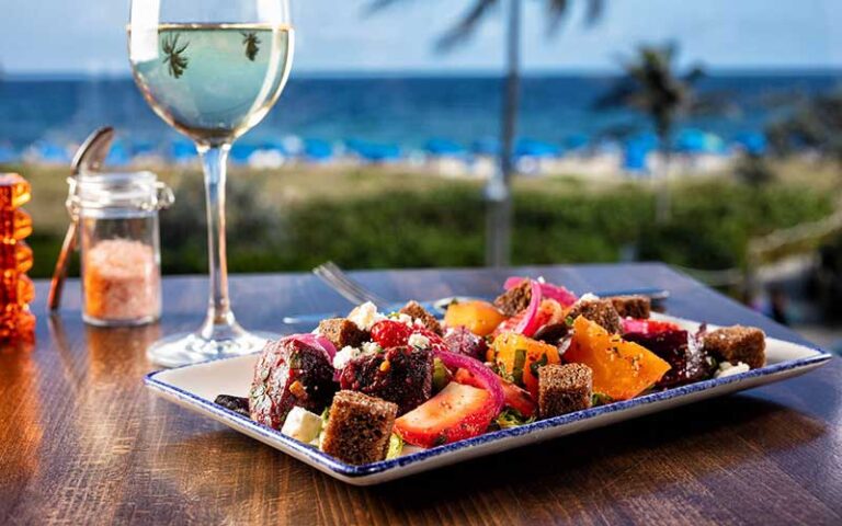 dinner entree with white wine and night beach view at the atlantic suites on the ave delray beach