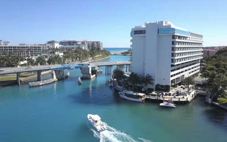 high rise hotel alongside waterway with boats and bridge at waterstone resort marina boca raton