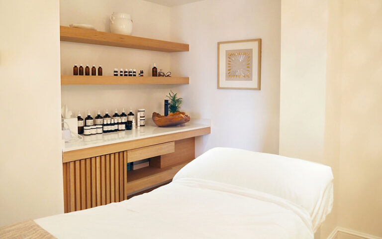 massage room with bed and shelves of oils at opal grand resort spa delray beach