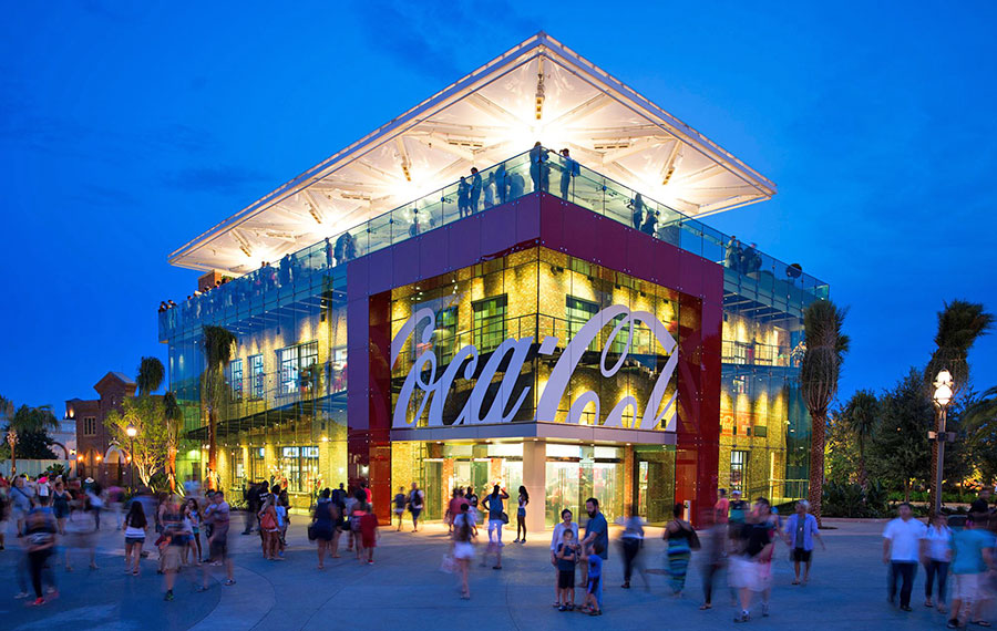 night exterior with blue lighting of crowded store with rooftop lounge area at coca cola store disney springs