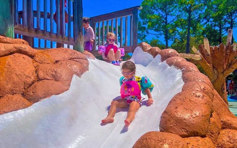 two toddler girls sliding down kiddie slide at shipwreck island waterpark panama city beach