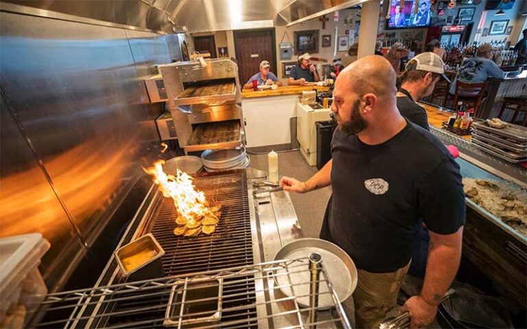 cook in open plan kitchen with dining area at dat cajun place cafe panama city beach