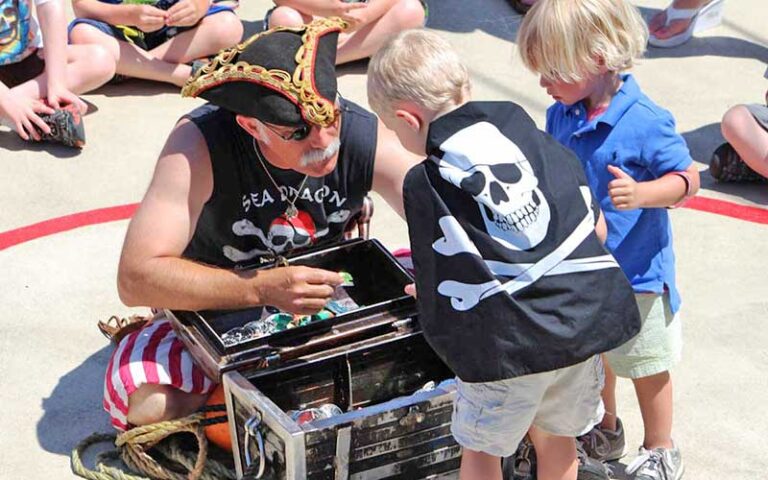 costumed pirate character helping kids look in treasure chest at sea dragon pirate cruise panama city beach