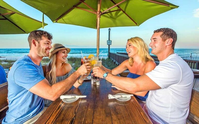 couples toasting drinks at oceanfront table at runaway island panama city beach