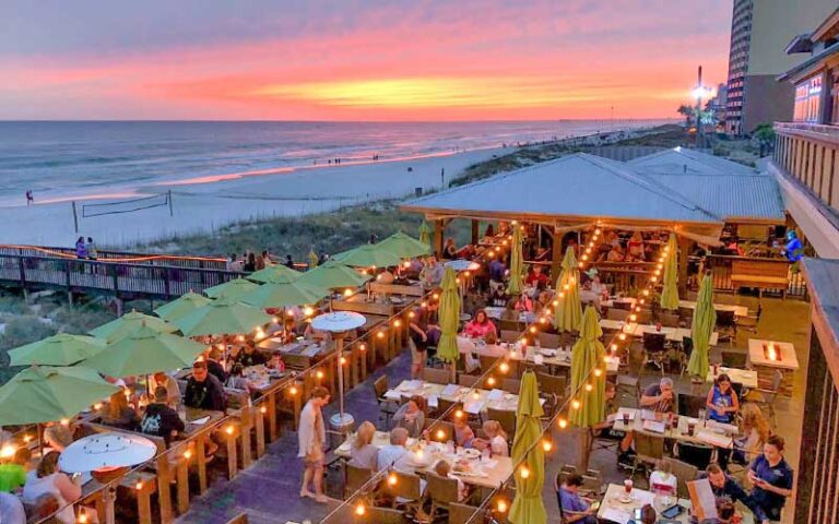 dining deck with string lights and sunset beach view at runaway island panama city beach